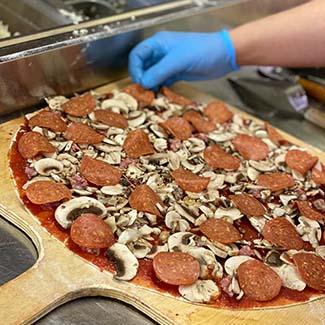 Preparing a Specialty Pizza to be cooked at Butch's Pizza The Best Pizza in Kimberly, WI